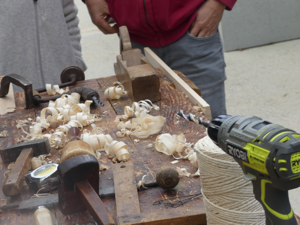 Photo d'un atelier "Woodlab" avec un établi, du bois et des outils